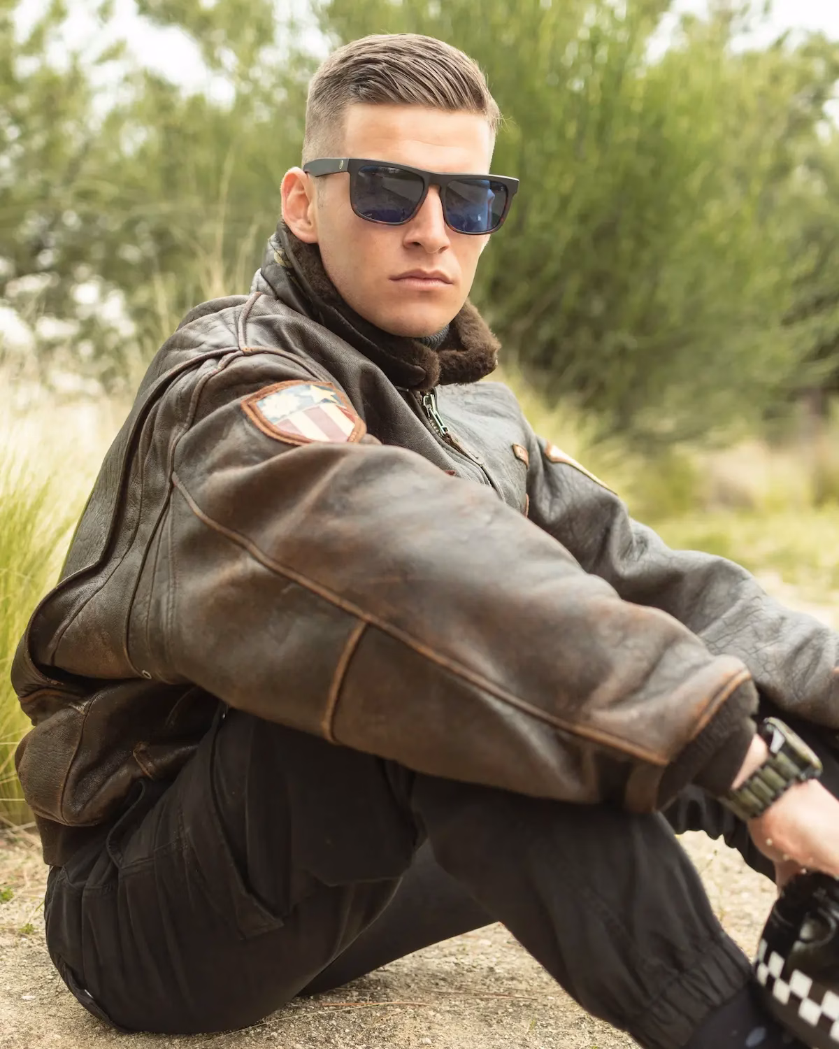 Modello uomo con occhiali da sole squadrati e giacca pelle trend vintage