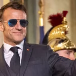 foto di Macron con pollice all insù , indossa occhiali da sole