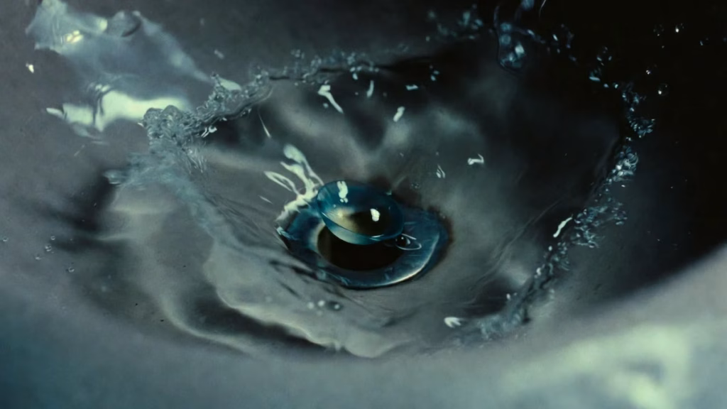 Una lente a contatto usa e getta che sta per cadere nello scarico del lavandino, illustrando l'errore comune di gettarle nel water o nel lavabo.